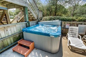 Un bain à remous avec une terrasse en bois, un escalier en bois et un panneau indicateur.