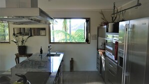 A modern kitchen with a large window, stainless steel appliances, and a granite countertop. - Our Tree house, private rural retreat . (Whakatane)