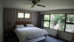 A bedroom with a bed, a ceiling fan, a window, and a view of trees. - Our Tree house, private rural retreat . (Whakatane)