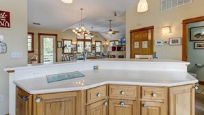 A spacious kitchen with a large island, pendant lighting, and wooden cabinetry. - Loafing Around In Duck | 1250 ft from the beach | Private Pool, Hot Tub | Duck (Duck)
