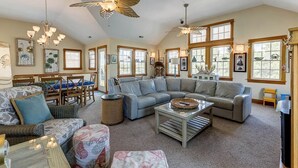 A spacious living room with a large sectional sofa, a coffee table, and a dining area with wooden chairs and a table. - Loafing Around In Duck | 1250 ft from the beach | Private Pool, Hot Tub | Duck (Duck)