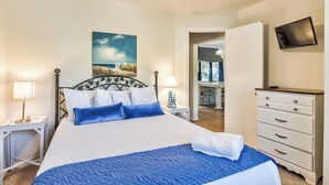 Una camera da letto con un letto, comodini, una cassettiera, una TV e un quadro appeso al muro.