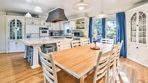 Una cucina moderna con mobili bianchi, un tavolo da pranzo in legno e luci a sospensione.