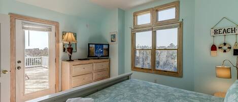 A bedroom with a bed, a dresser, a television, and a window with a view.