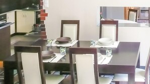 Un comedor con una mesa rectangular, cuatro sillas y una cocina al fondo.