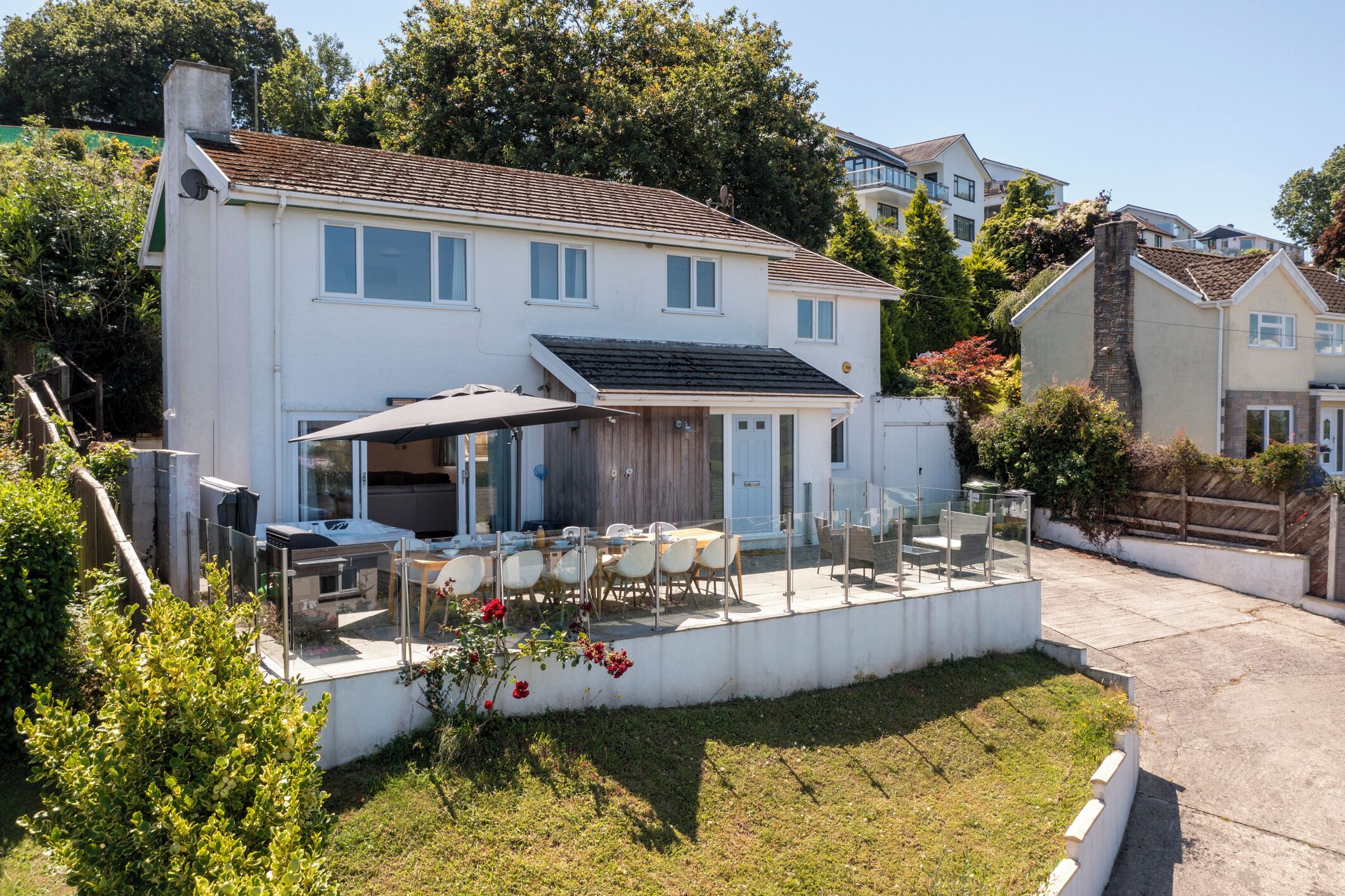 A two-story house with a patio area featuring outdoor furniture and a covered seating area.