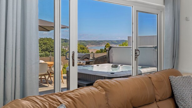 A room with a sliding glass door leading to an outdoor area with a hot tub and a scenic view of the landscape.