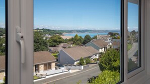 A residential street with houses, a clear blue sky, and a distant body of water.
