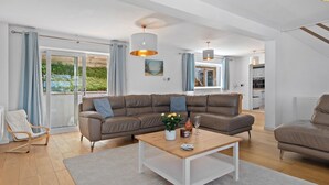 A modern living room with a sectional sofa, a coffee table, and a dining area.