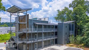 A multi-story building with balconies, a parking lot, and a stop sign. - Studio King Suite w/ Kitchen | 200 (Asheville)