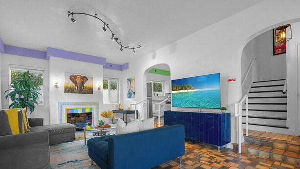 Ein modernes Wohnzimmer mit Kamin, großem Fernseher und einer Treppe, die in ein Obergeschoss führt.