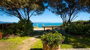 Un jardin avec un banc, un jardinier avec des fleurs et une vue sur la mer.