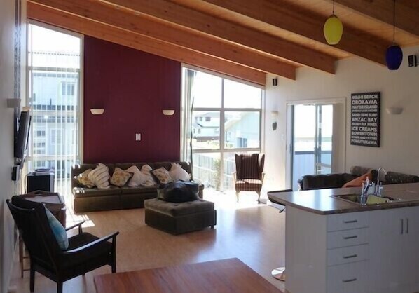 A spacious living area with a sofa, a dining table, and a kitchen area with a sink.