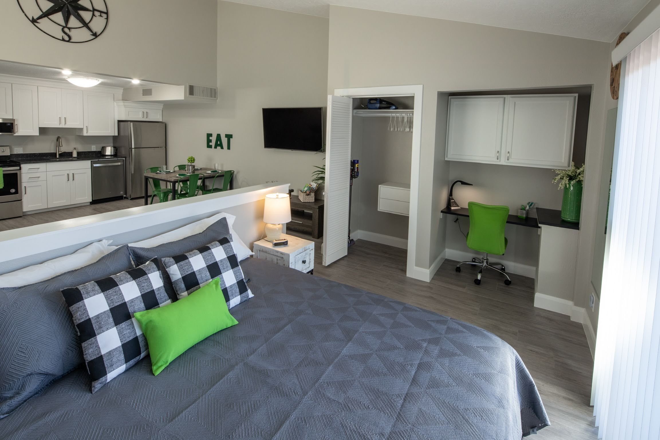 A compact hotel room with a bed, a small kitchenette, a dining area, and a walk-in closet.