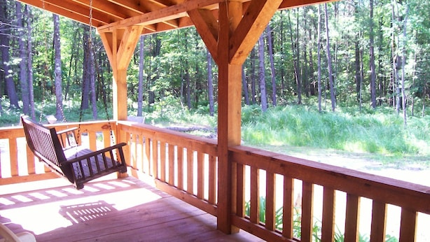 A wooden deck with a swing and a bench, overlooking a forested area. - Private Amish Log Cabin Getaway (Black River Falls)