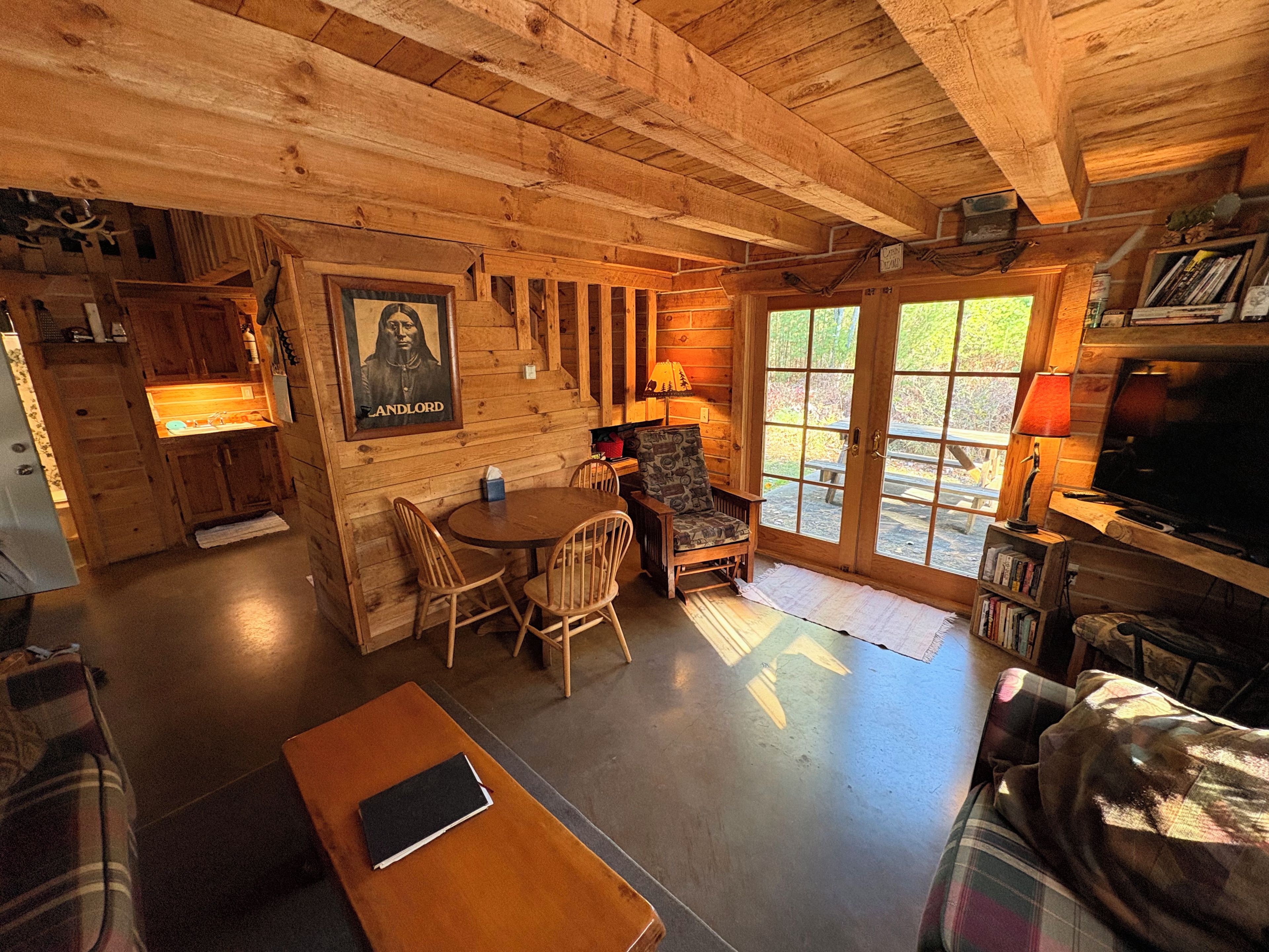 A cabin interior with a dining area, a television, and a bookshelf.