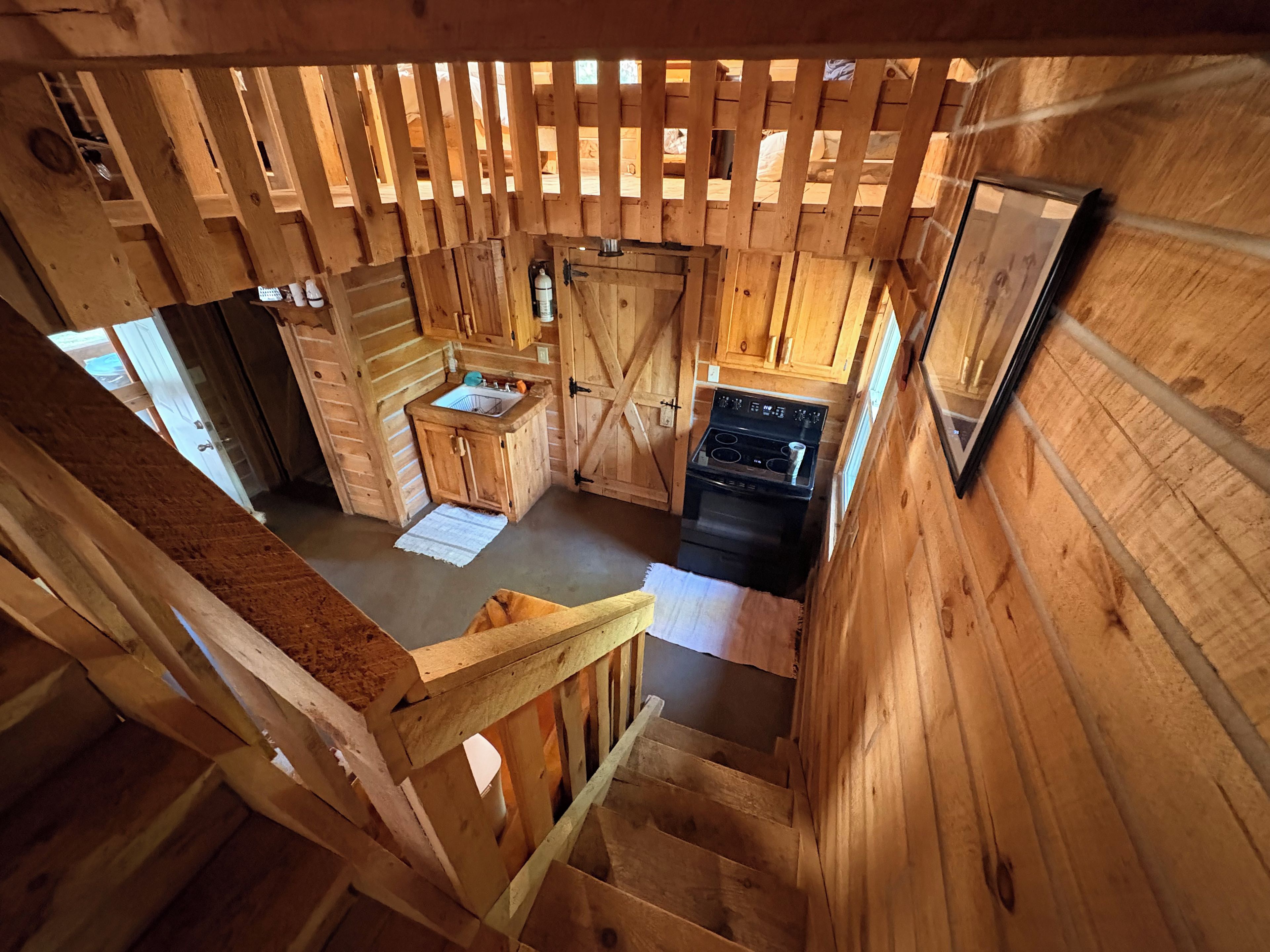 A wooden cabin interior with a kitchen area, including a stove, sink, and cabinets.