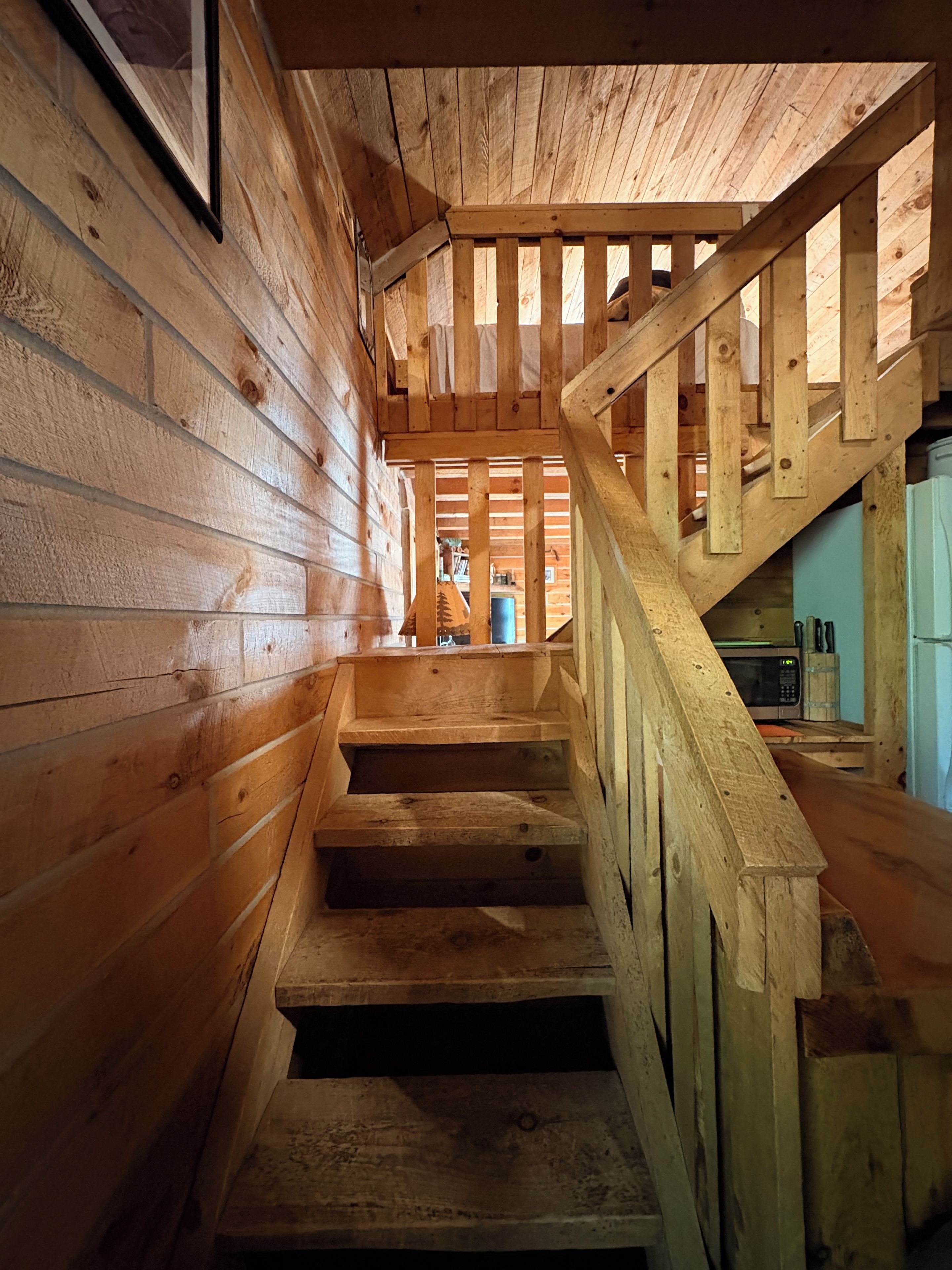 A wooden staircase leading to a second floor with a kitchen area visible in the background.