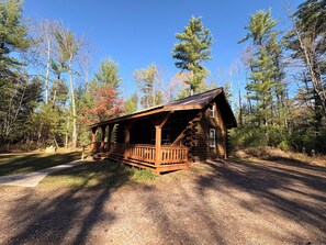 A rustic cabin with a porch, surrounded by a forest. - Private Amish Log Cabin Getaway (Black River Falls)