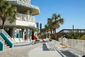 A resort with a pool, lounge chairs, palm trees, and a staircase leading to a balcony. - Oceanfront Suite w/ Incredible View + Official On-Site Rental Privileges (Myrtle Beach)