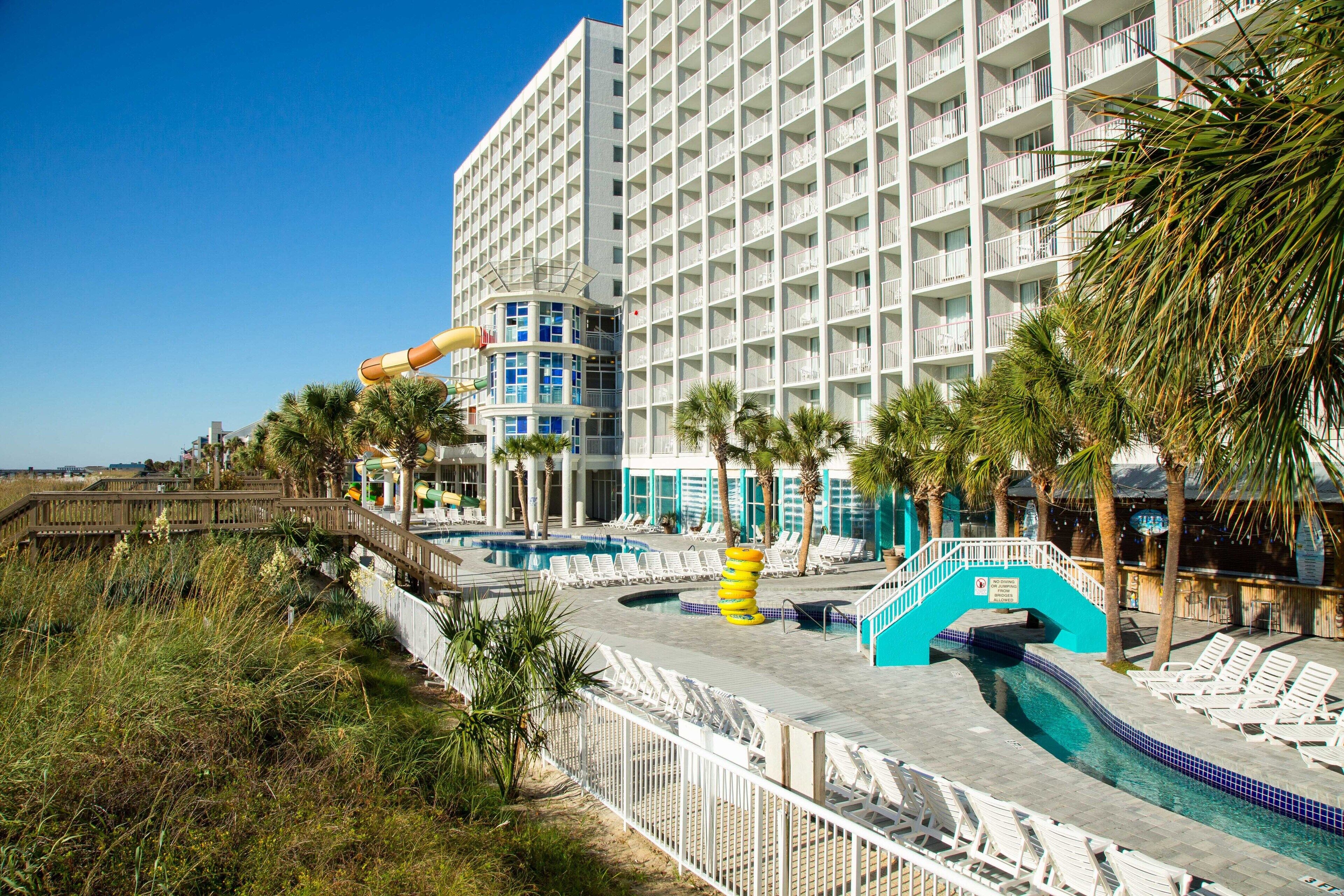 A hotel with a pool area, including a water slide and lounge chairs.