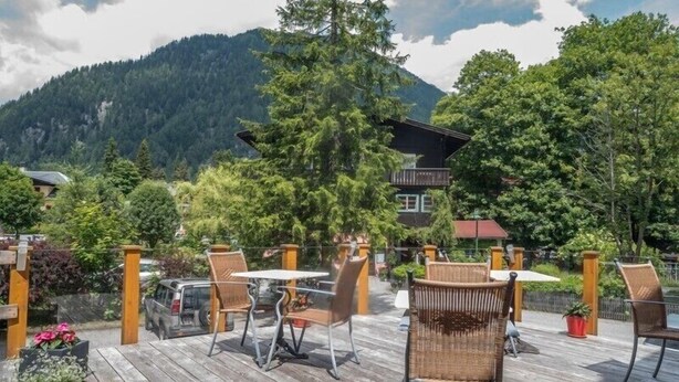 An outdoor deck with wicker furniture and a mountain view. - Hotel Kärntnerhof Mallnitz (Mallnitz)