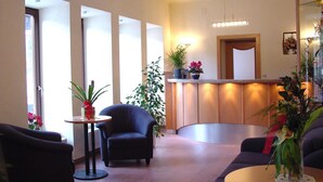 A modern lobby with a reception desk, seating area, and potted plants. - Hotel Kärntnerhof Mallnitz (Mallnitz)