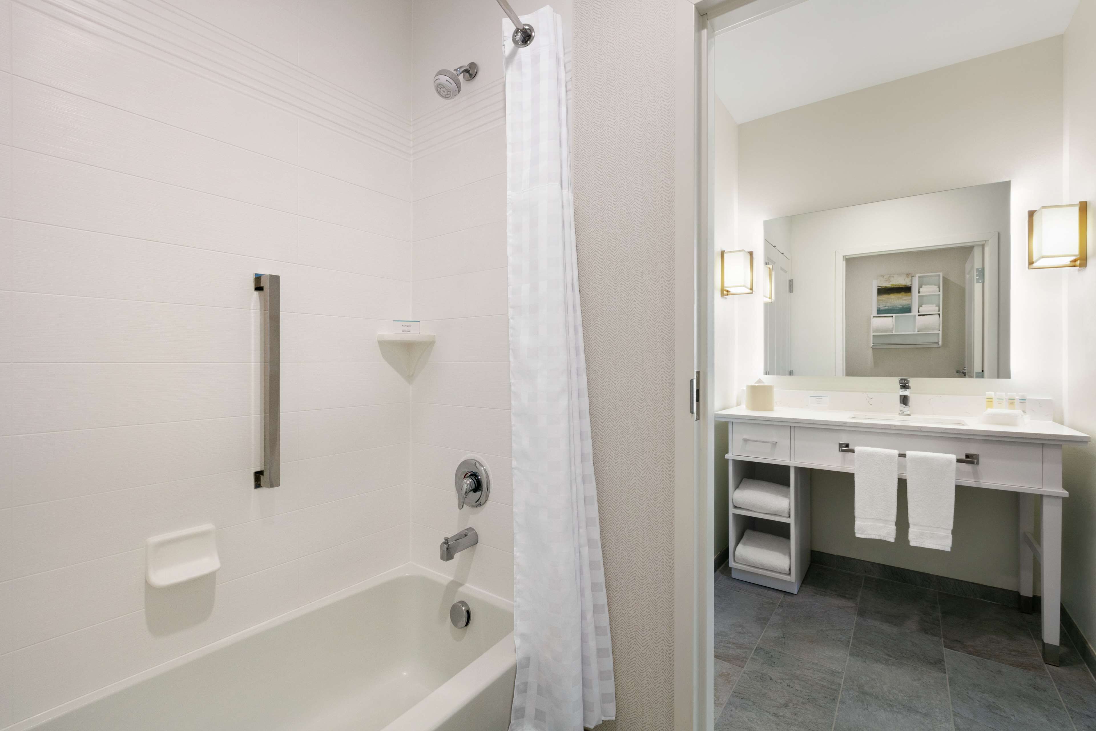 Un baño moderno con bañera, ducha y tocador con espejo y perchero.
