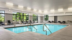An indoor swimming pool with clear glass walls, sun loungers, and a tiled floor. - Homewood Suites by Hilton Horsham Willow Grove (Horsham)
