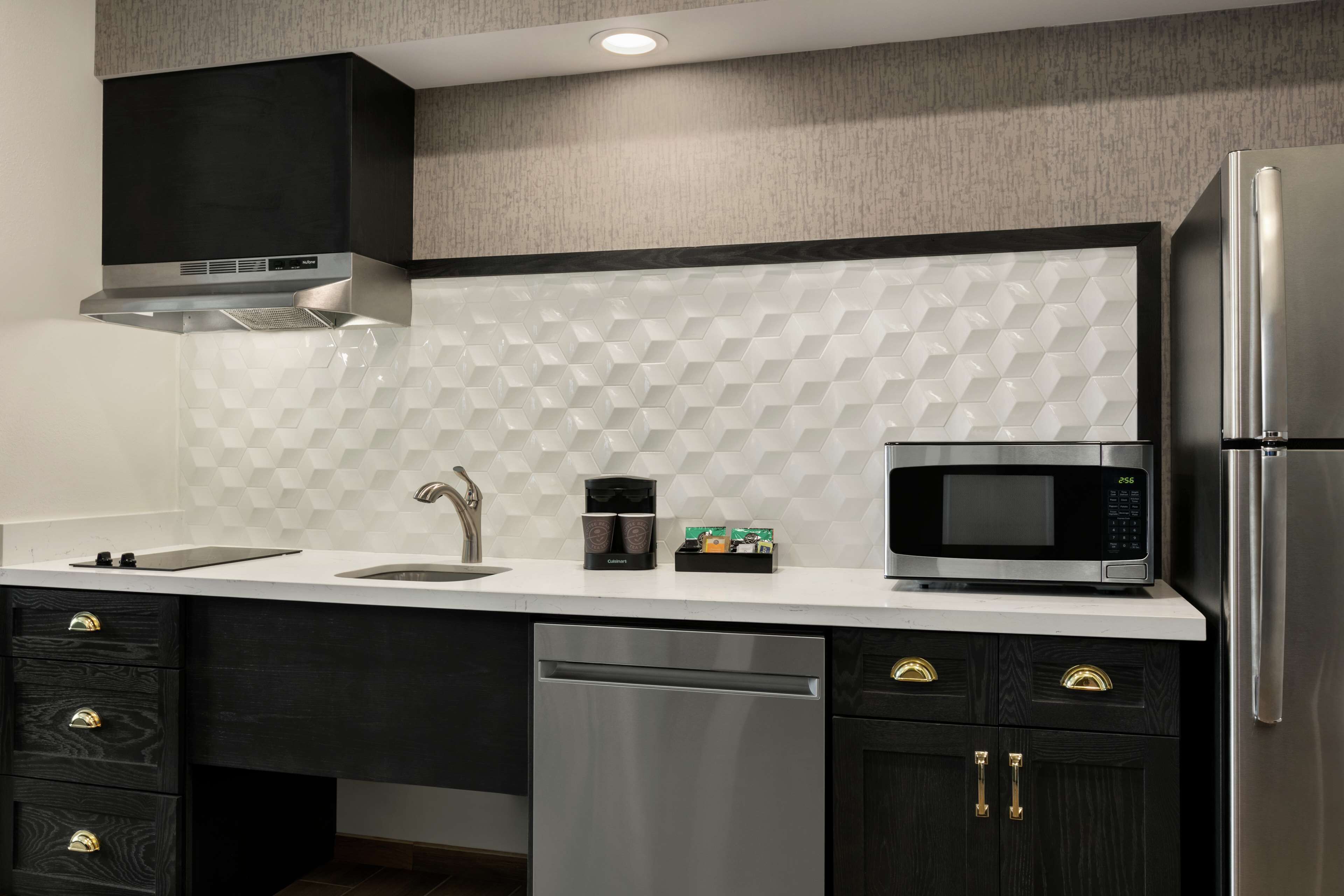 A modern kitchen with a stainless steel refrigerator, microwave, and dishwasher.