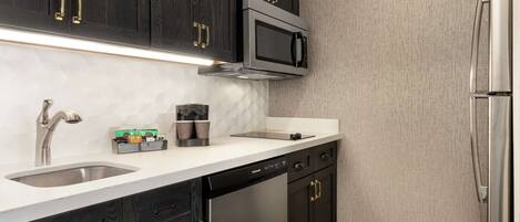A modern kitchen with dark wood cabinets, stainless steel appliances, and a white countertop.