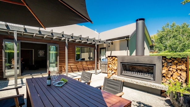 Une terrasse extérieure avec une table en bois, des chaises et un espace barbecue.