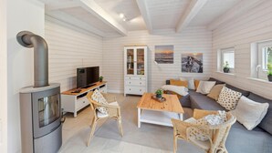 Una habitación acogedora con chimenea, televisor, sofá y una mesa de comedor.