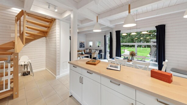 Una cocina moderna con armarios blancos, encimera de madera y una escalera espiral integrada.
