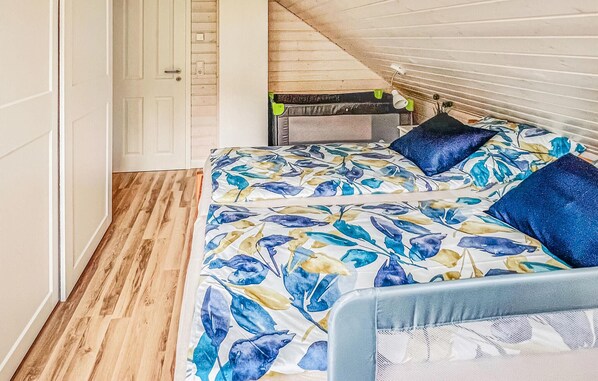 Een slaapkamer met een bed, voorzien van een bloemenbedekking, een hoofdbord en twee kussens.