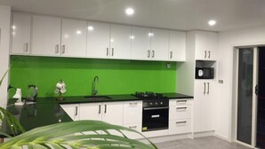 Une cuisine moderne avec des meubles blancs, un pare-feu vert et un plan de travail noir.