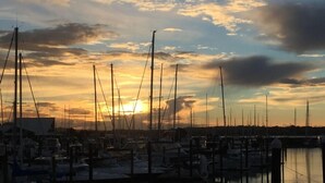 Un port de plaisance où de nombreux bateaux sont amarrés à des quais en bois, le tout se détachant sur le ciel au coucher du soleil.
