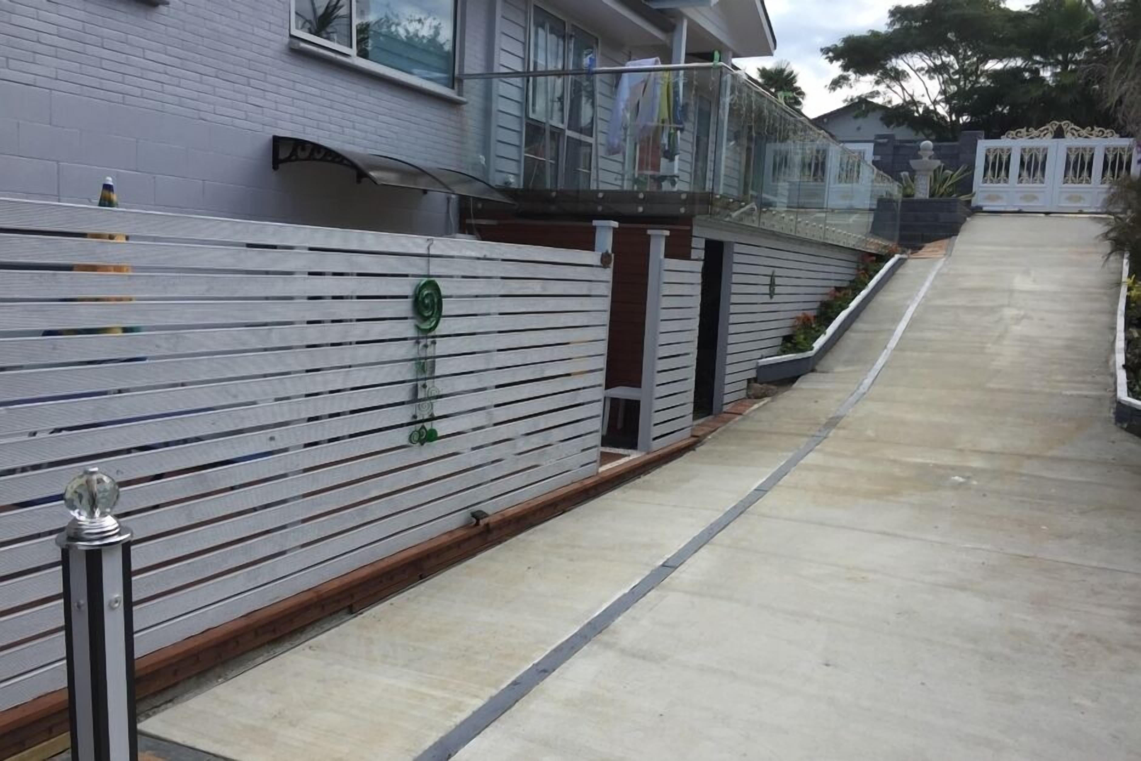 A residential area with a concrete pathway leading to a gated entrance.