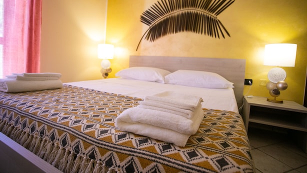 Une chambre d’hôtel avec un lit, une couverture à motifs, un élément décoratif fixé au mur et deux lampes de chevet.