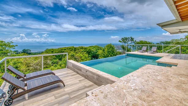 A pool area with lounge chairs, a view of the ocean, and a wooden deck. - Exclusive Pool Oasis: Stunning Views! Sleeps 8, Nature's Seclusion (Puntarenas)