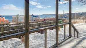A wooden deck with a view of a snowy landscape and buildings in the distance.