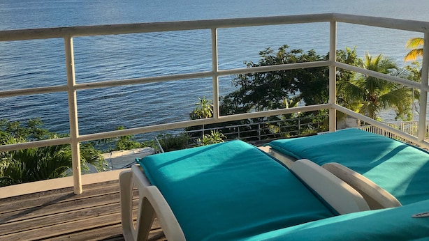 A balcony with two lounge chairs and a view of the ocean.