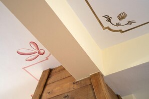 A corner of a room with a wooden floor and a white wall with a decorative design. - Alpine Aria (Kalavrita)