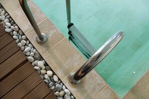 A poolside area with a metal handrail, pebbles, and tiled flooring. - Alpine Aria (Kalavrita)