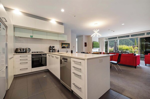 A modern kitchen with white cabinetry, a dishwasher, and a coffee machine. - Edgar Rise, 500m from Queenstown CBD (Queenstown Hill)
