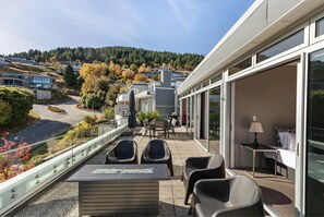 A balcony with outdoor seating, a table, and a view of a residential area with houses and trees. - Edgar Rise, 500m from Queenstown CBD (Queenstown Hill)