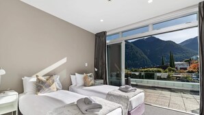 Ein Hotelzimmer mit zwei Betten, einem großen Fenster mit Bergblick und einem Balkon mit Geländer.