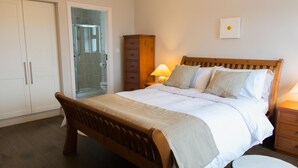 Une chambre à coucher avec un lit en bois, une table de chevet avec une lampe, une armoire et un espace douche.