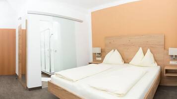 Une chambre d’hôtel moderne avec un lit en bois, une cabine de douche en verre et un plafond incurvé.