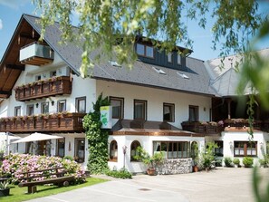 A two-story building with balconies, a stone facade, and outdoor seating. - Double room with extra bed - Pension Irlingerhof *** (Guggenberg)